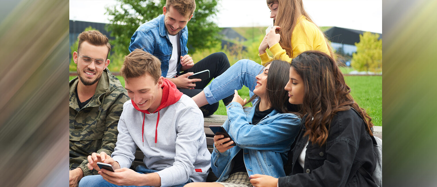 Jugendliche | Generation Z Jugendliche Gruppe sitzt zusammen und schaut auf Smartphones