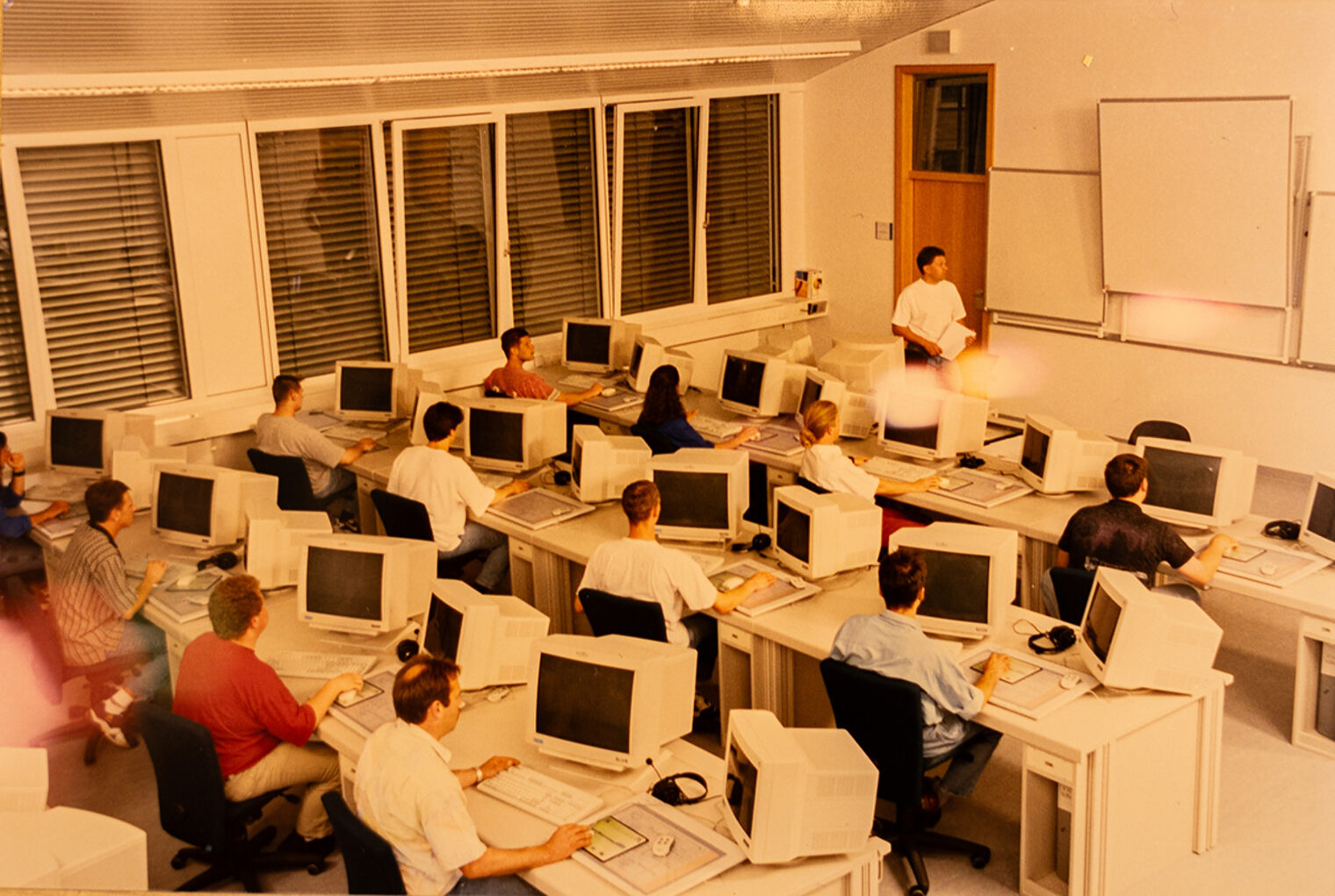 Foto der Akademie für Unternehmensführung, 1980, eine große Klasse sitzend an Röhrenmonitoren