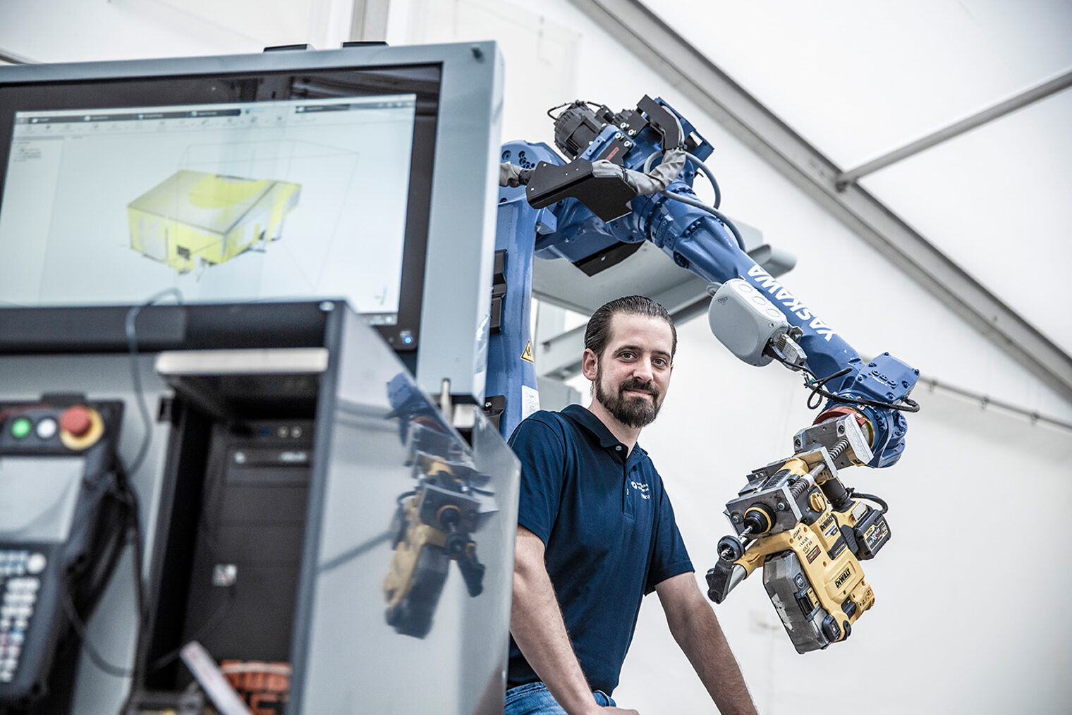 Junger Mann in einer Werkstatt neben einem Roboterarm