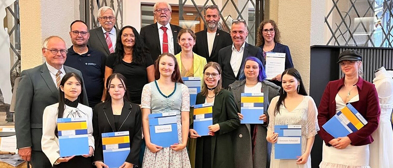 Gruppenfoto mit Vertretern des Handwerks und jungen Auszubildenden aus dem Bekleidungshandwerk mit Abschlusszeugnissen