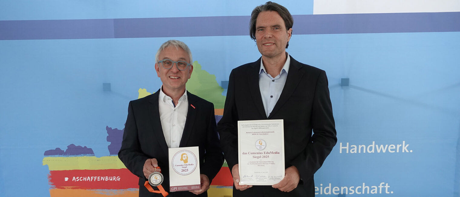 Foto zweier Personen, die Kamera blicken und Auszeichnung in den Händen halten