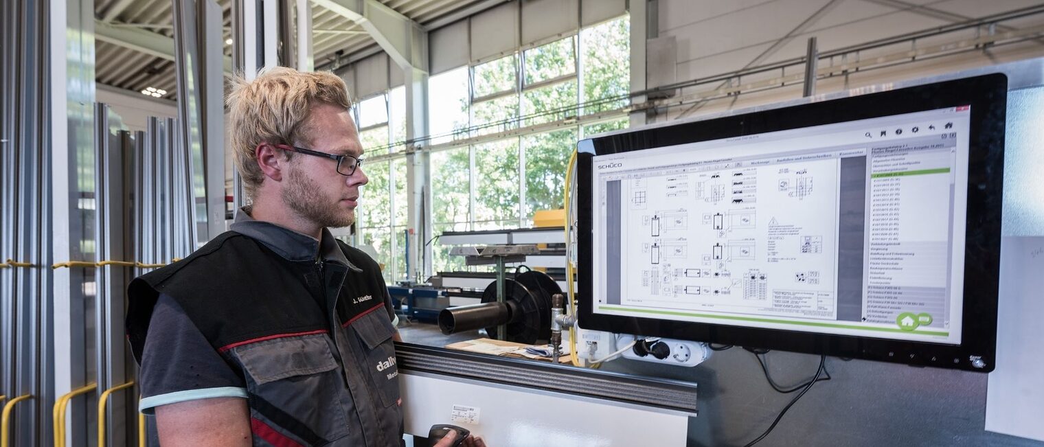 Ein Mann steht vor einem großen Bildschirm und prüft ein Gerät