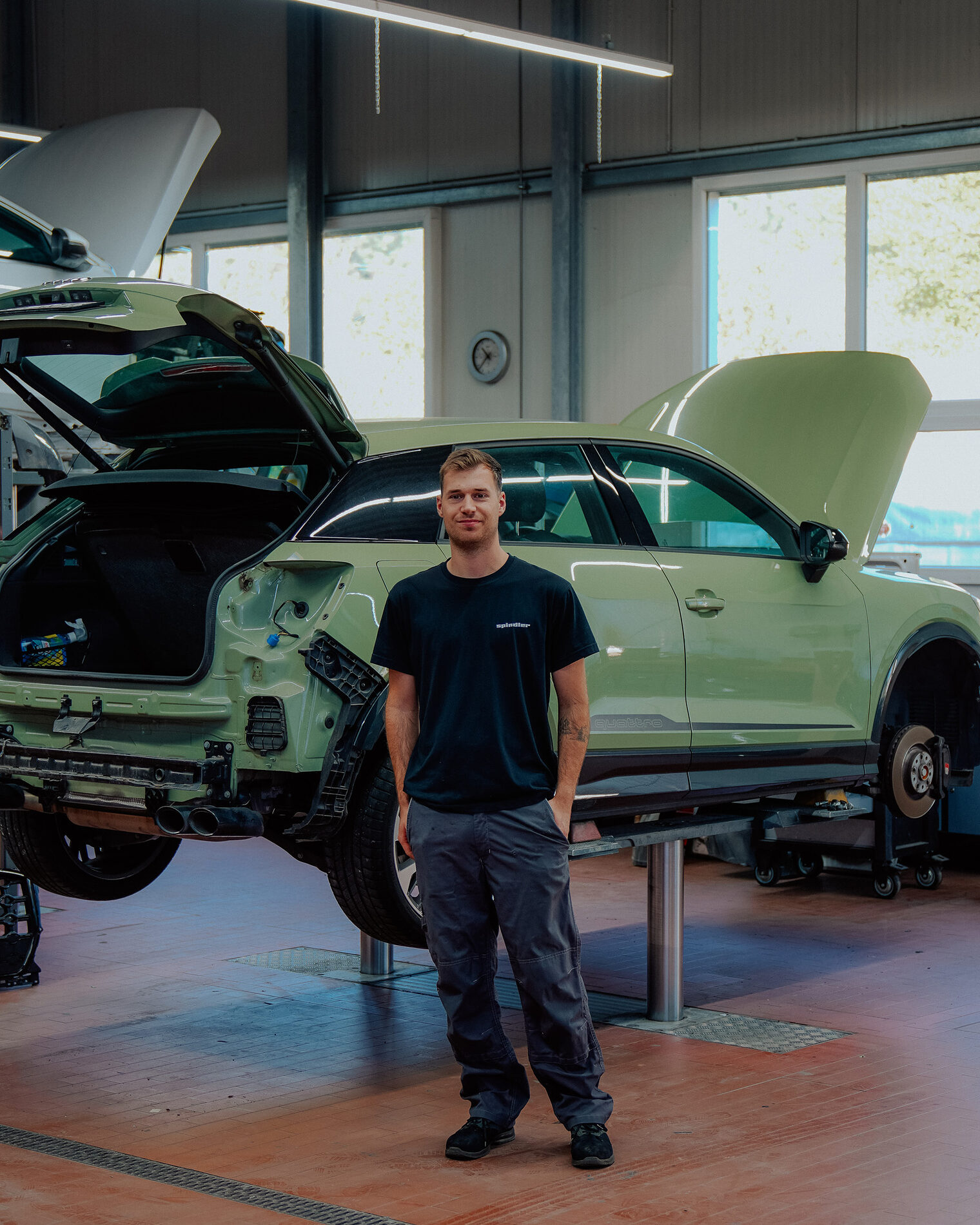 Geselle vor Karosserie in Werkstatt