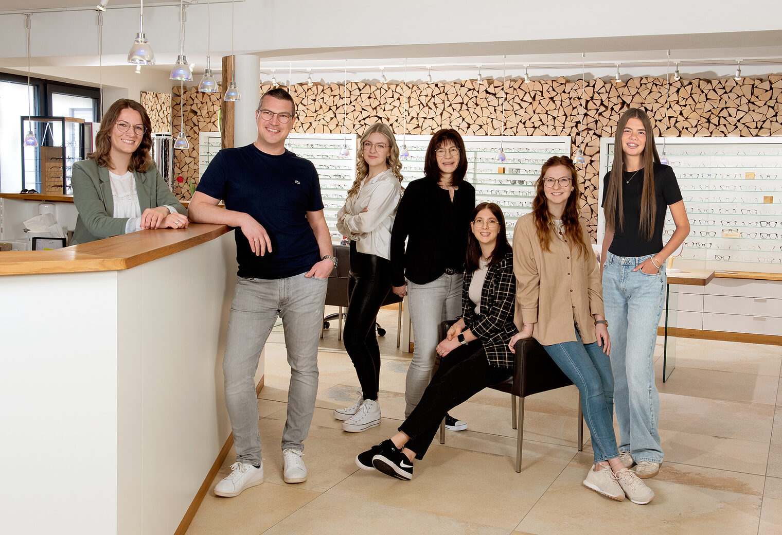 Auf dem Bild sieht man sieben Personen. Im Hintergrund sieht man viele Brillen
