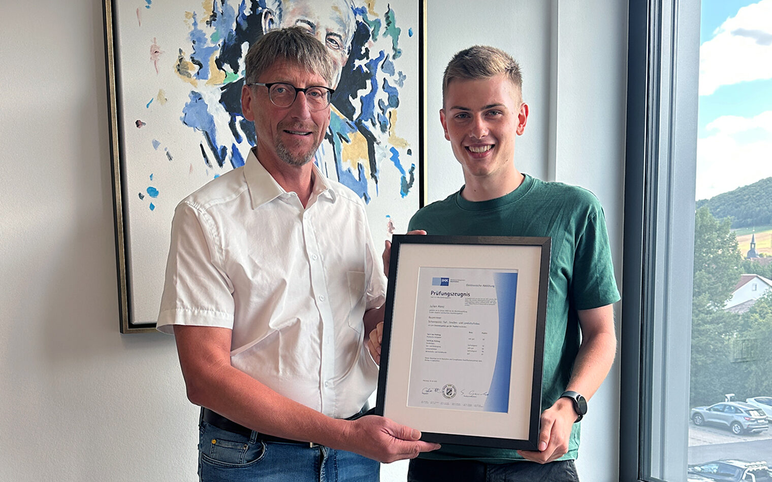 Zwei Personen halten eine Ehrung in der Hand