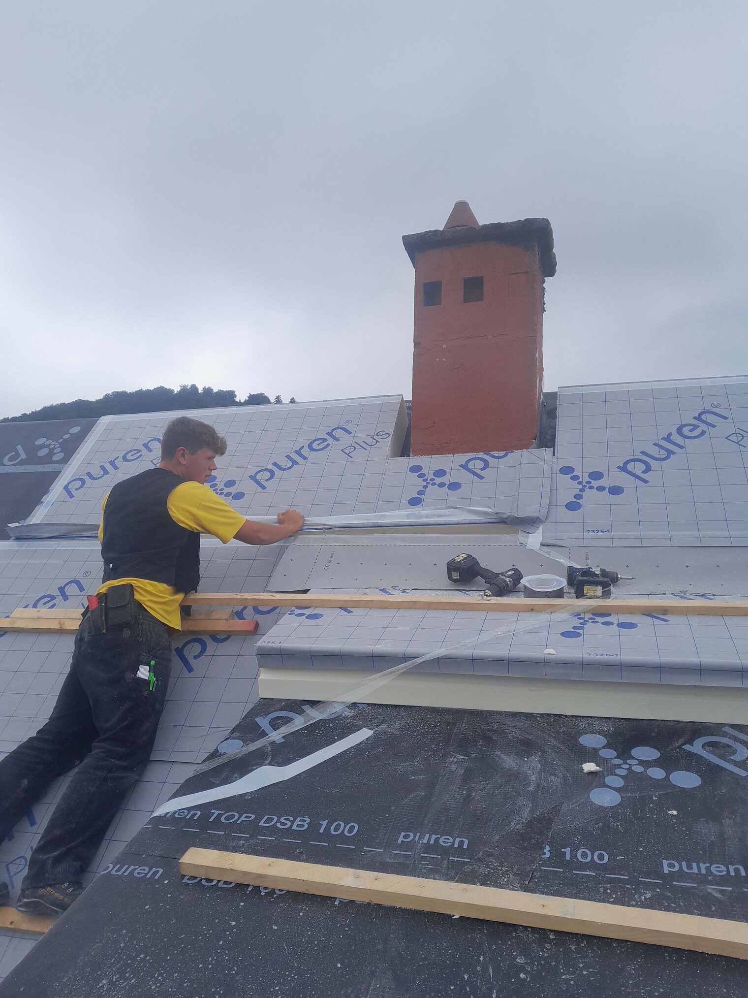 Dachdecker steht auf einem Dach und repariert ein Dach