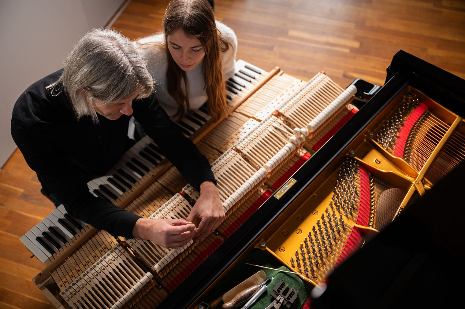 Mann und junge Frau schauen sich Hammerköpfe eines Flügels an