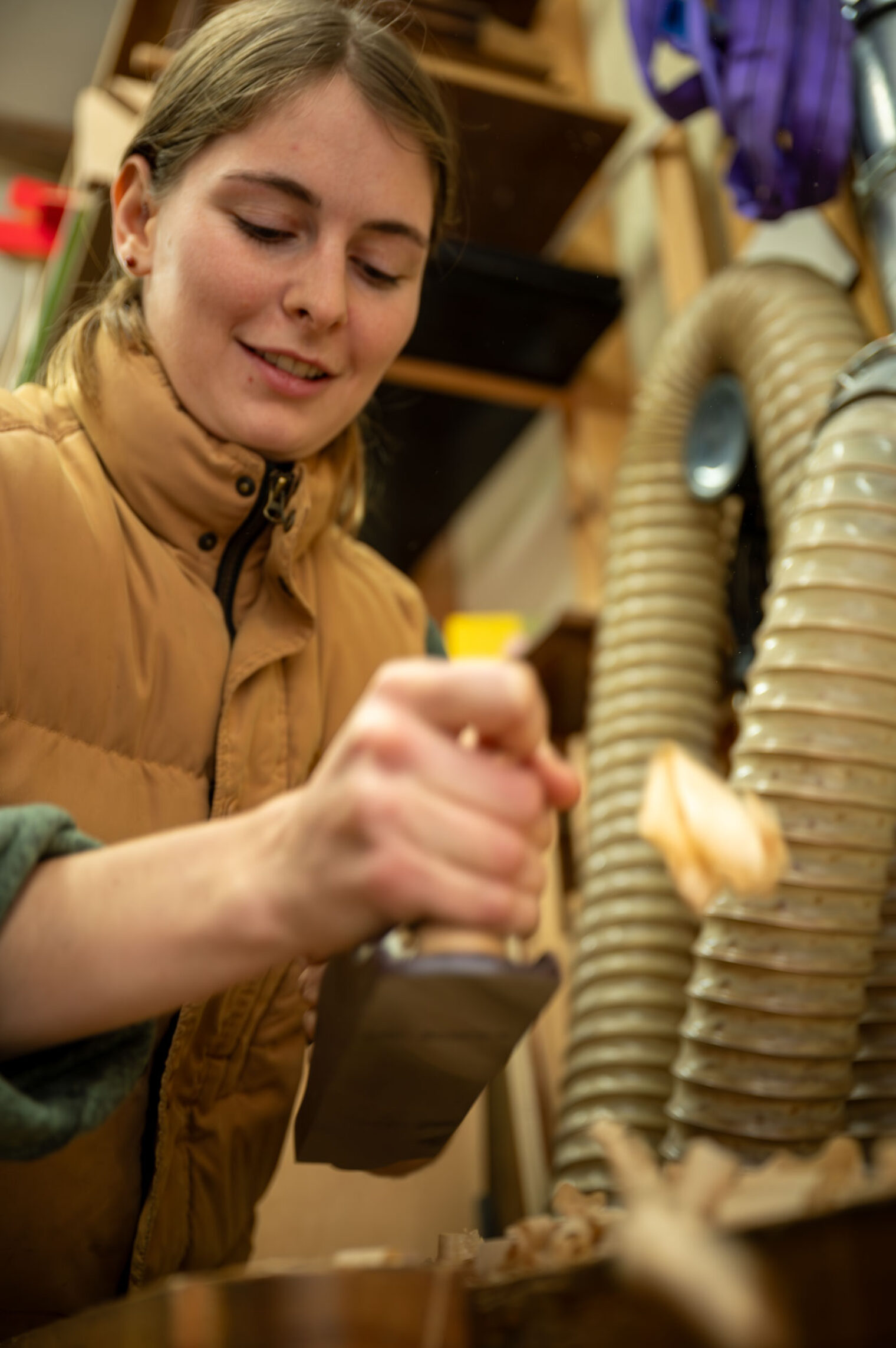Junge Frau in Werkstatt hobelt Holz