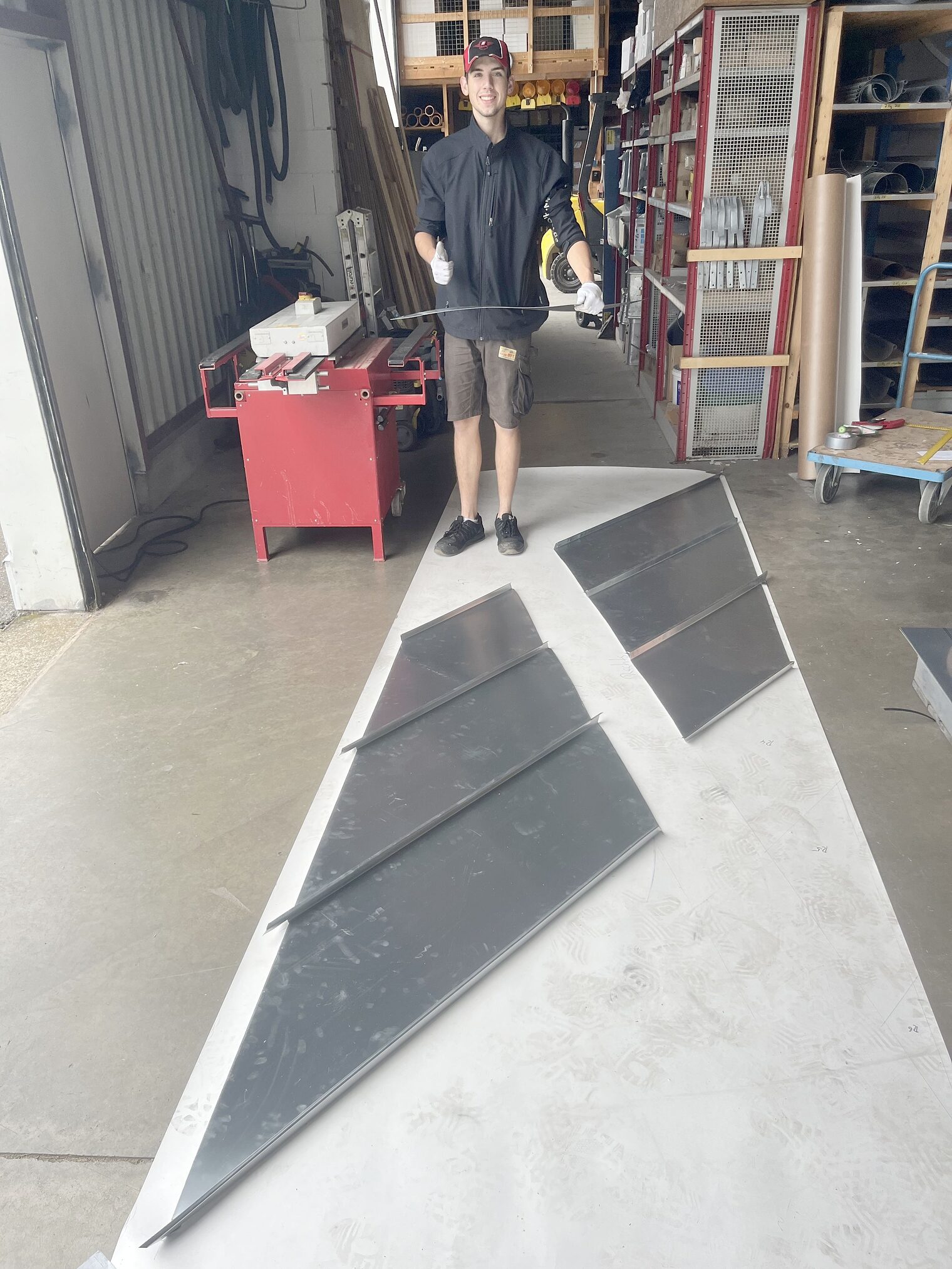 Junger Mann steht vor flacher Metallkonstruktion, zeigt Daumen nach oben