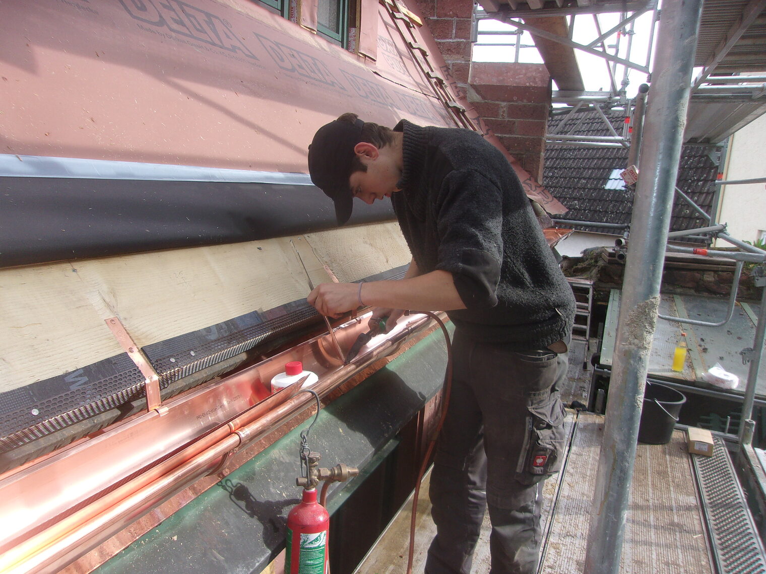 Junger Mann arbeitet an einer Dachrinne