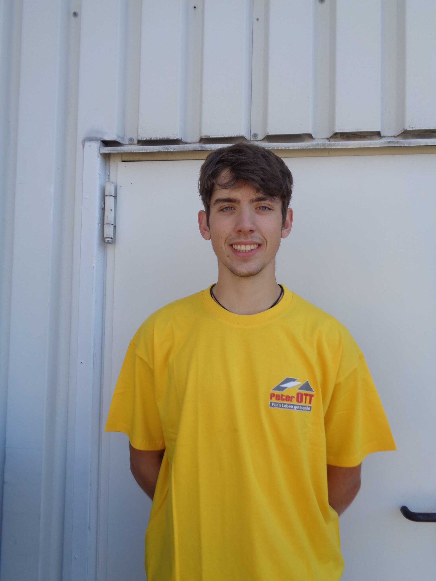 Junge in knallgelbem T-Shirt lächelt in die Kamera