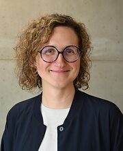 Portrait: Frau mit Locken und runder Brille lächelt in die Kamera Portrait: Frau mit Locken und runder Brille lächelt in die Kamera