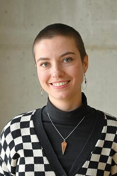 Portrait: Frau mit kurzen Haaren lächelt in die Kamera, Schwarz-Weiß karierter Pullover