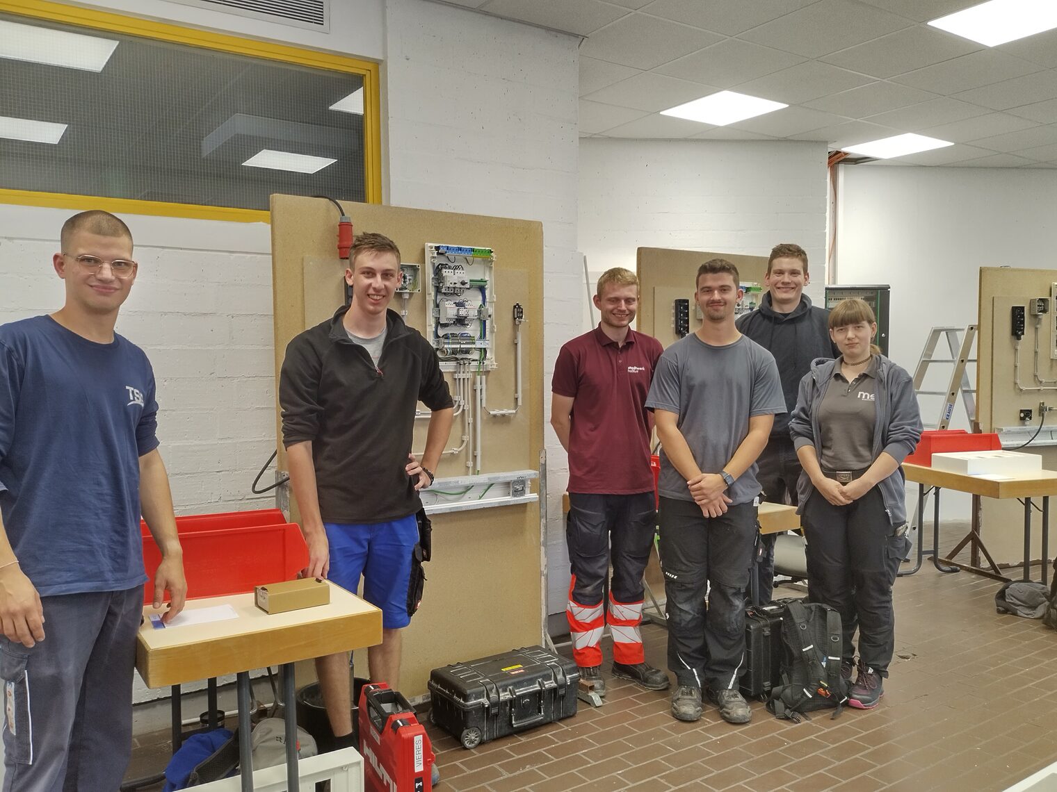 Gruppenbild: 5 Elektroniker, 1 Elektronikerin in Arbeitskleidung