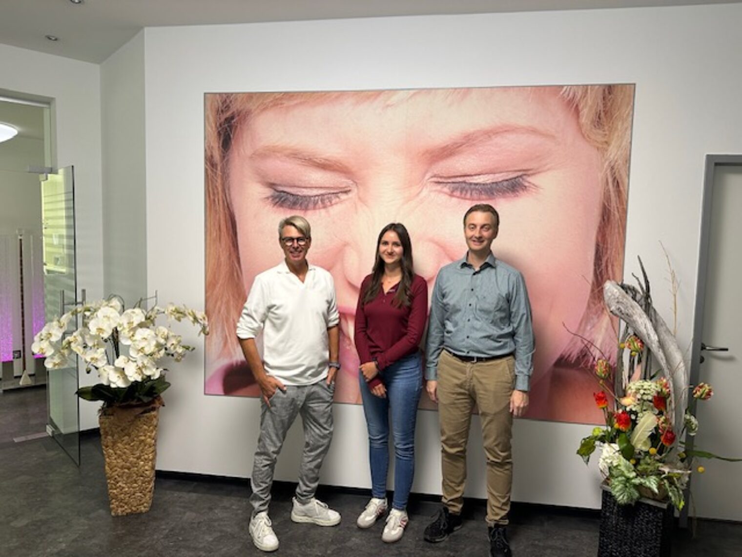 Drei Personen in Foyer des Dentallabors schauen in Kamera