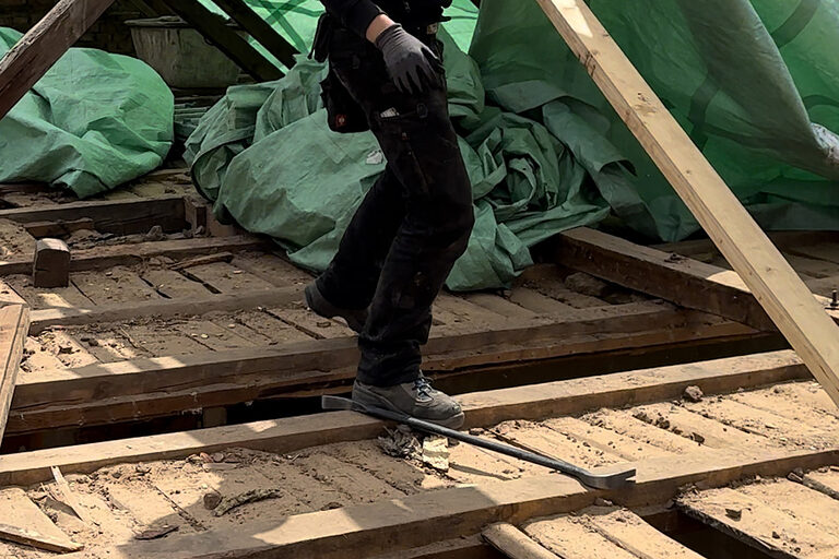 Zimmerer auf Baustelle, trägt einen Balken