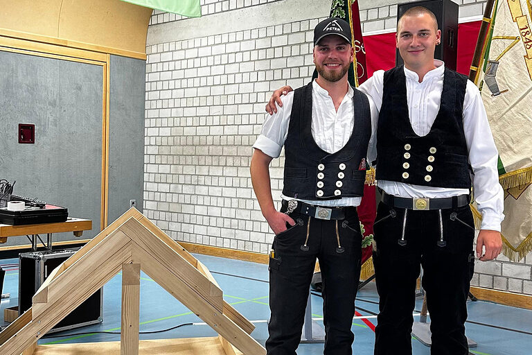 Zimmerer mit seinem Ausbilder vor Gesellenstück, einer Dachkonstruktion