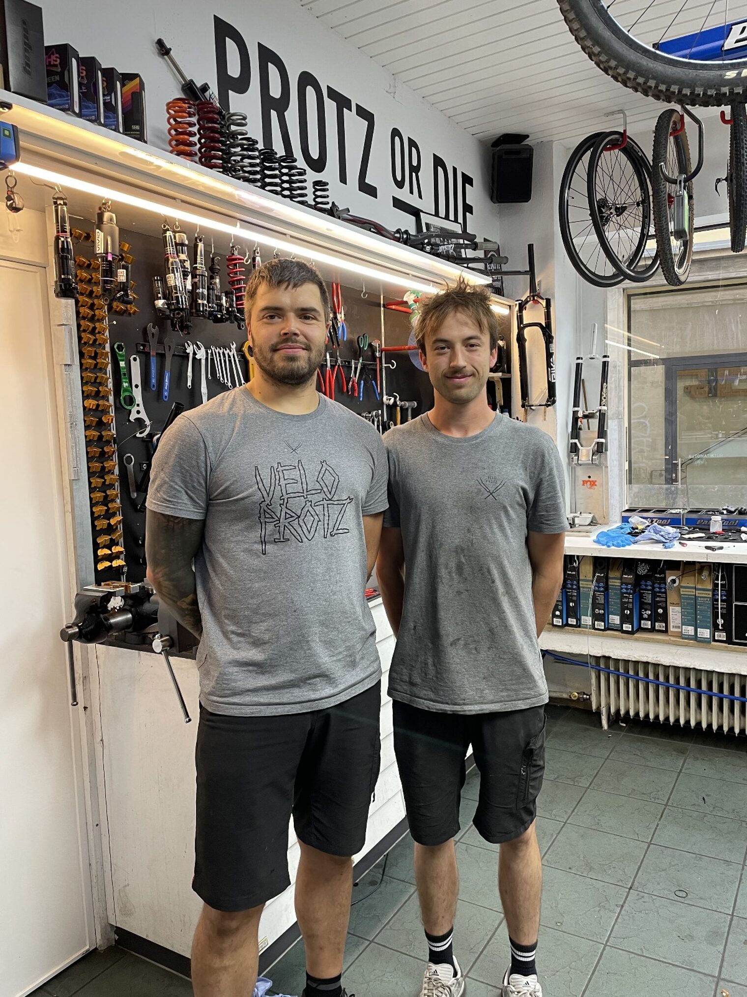 Azubi und Ausbilder in Fahrradwerkstatt, schauen in Kamera