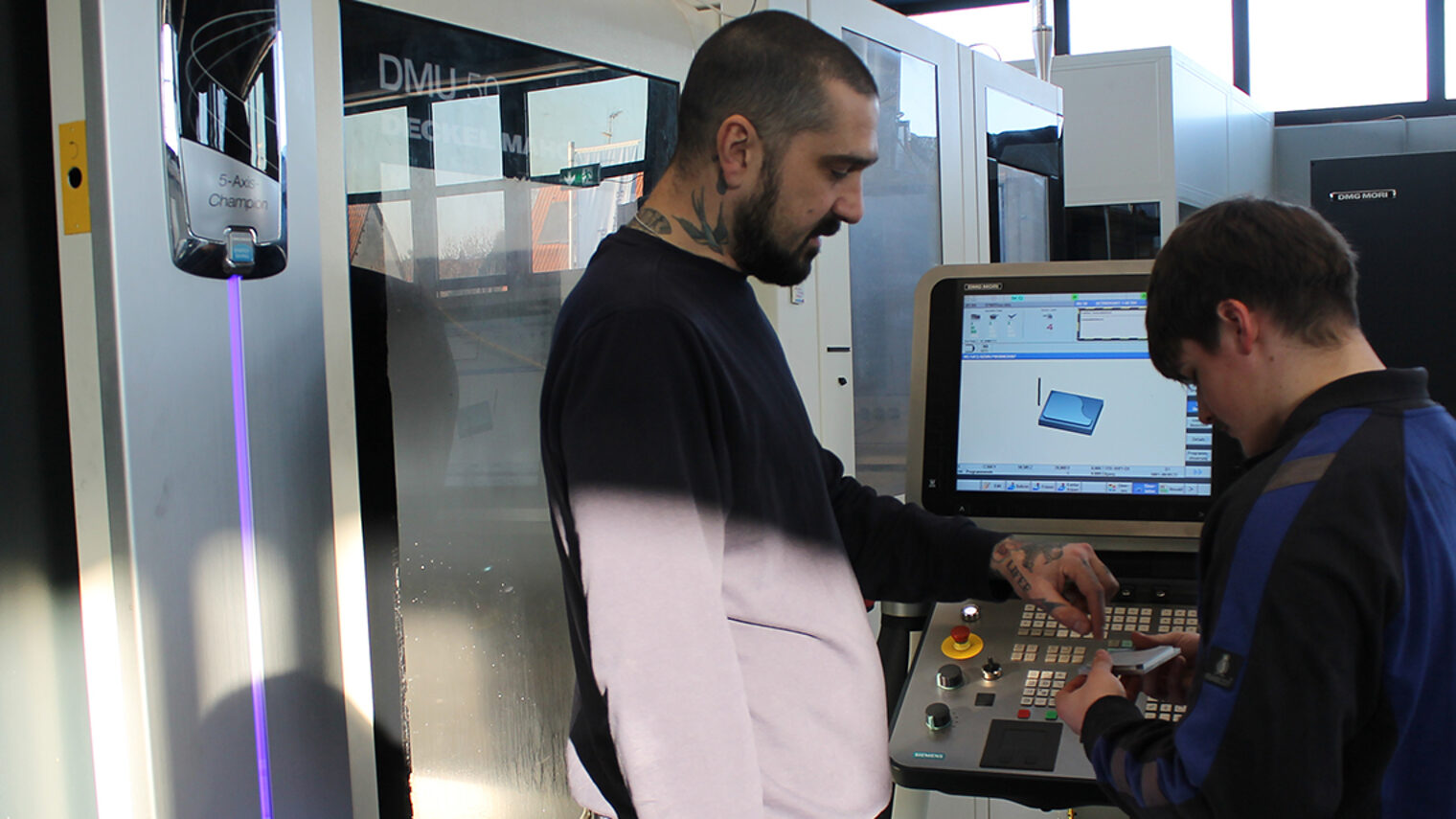 Schüler eines CNC-Intensivkurses an der Drehmaschine im Gespräch mit Feinwerktechnik Ausbilder im Bildungszentrum Aschaffenburg