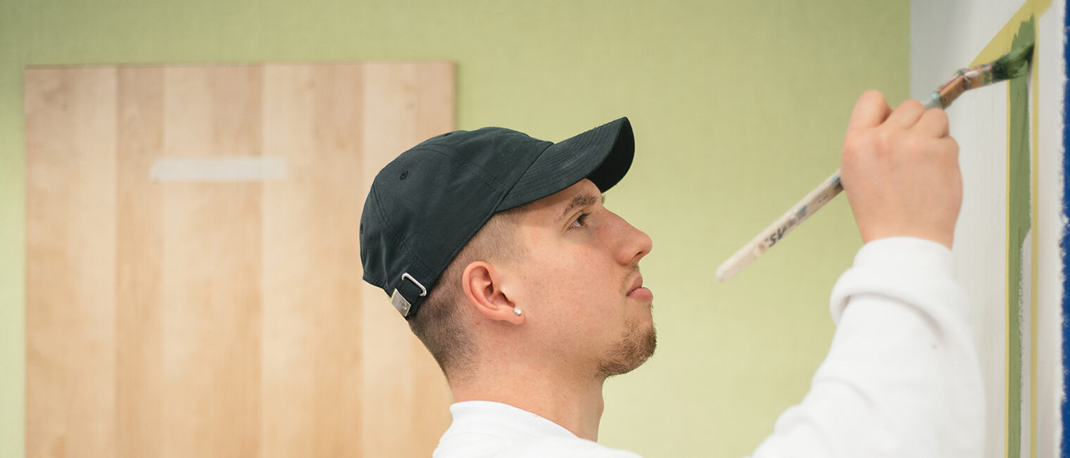 Maler- und Lackierer-Azubi streicht Wand bei der Überbetrieblichen Lehrlingsunterweisung im Bildungszentrum Aschaffenburg