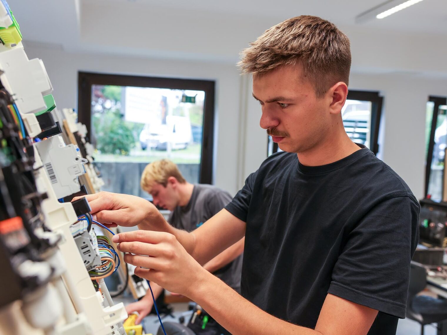Elektroniker schraubt Kabel an Brett