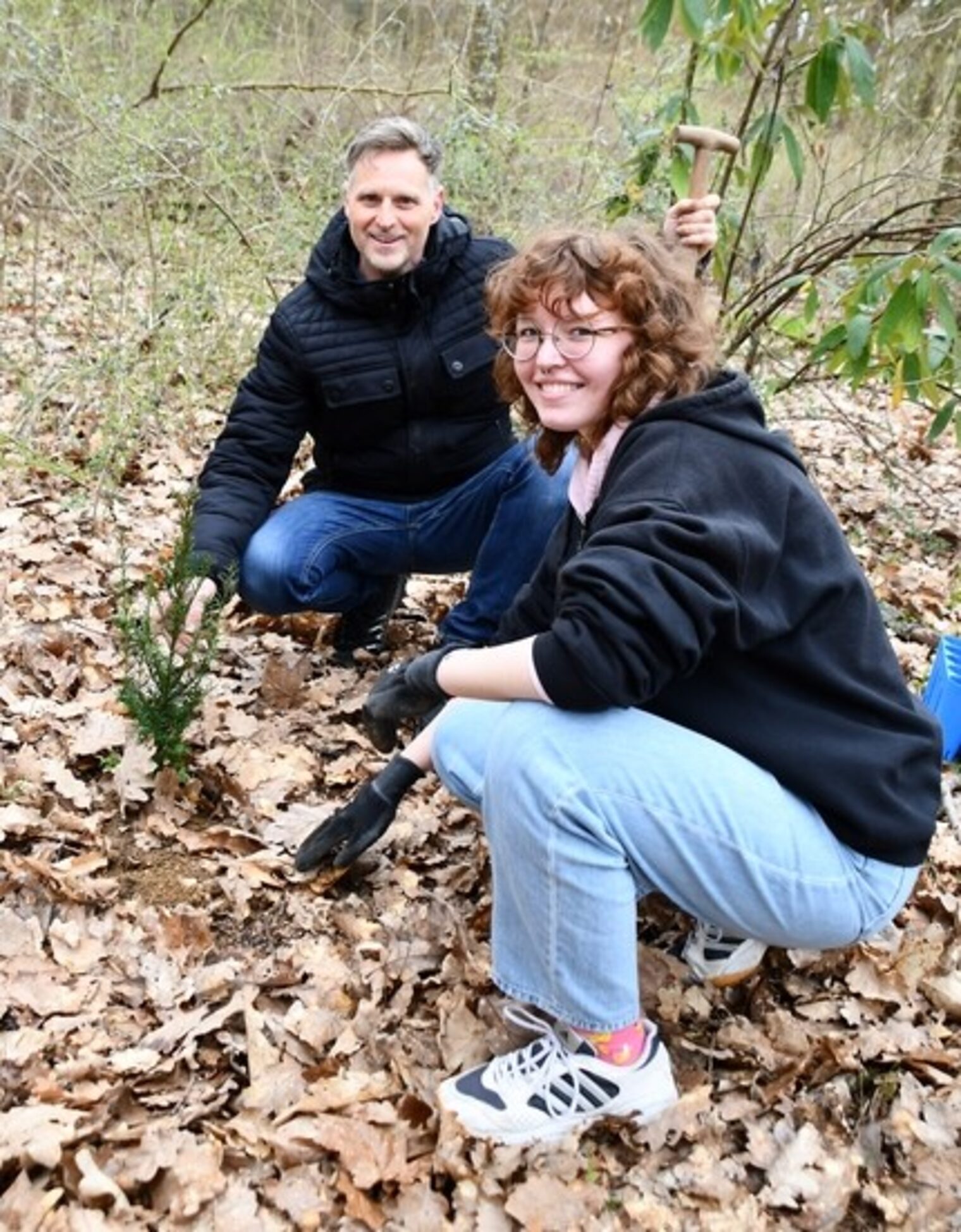 zwei Personen im Wald, schauen sich Muster am Boden an
